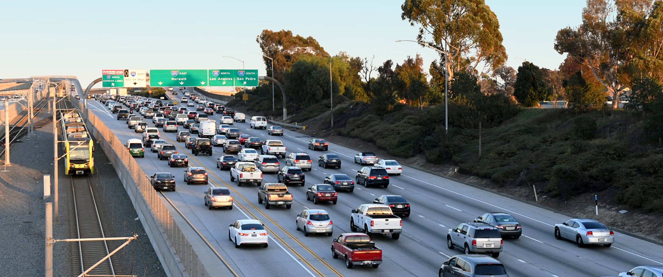 Freeway along I-105 ExpressLanes Project with cars sitting in traffic and a Metro light rail train..