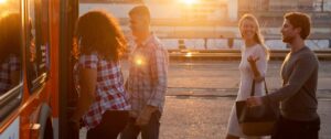 Four people boarding a Metro Bus with sun setting in background.