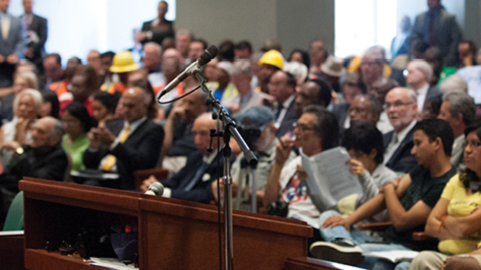 Crowded Board Meeting with microphone in the foreground.