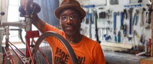 Man with bicycle in repair shop.