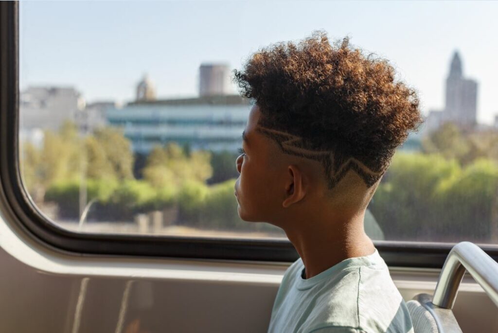 A young person sitting on the train and looking out of the window.