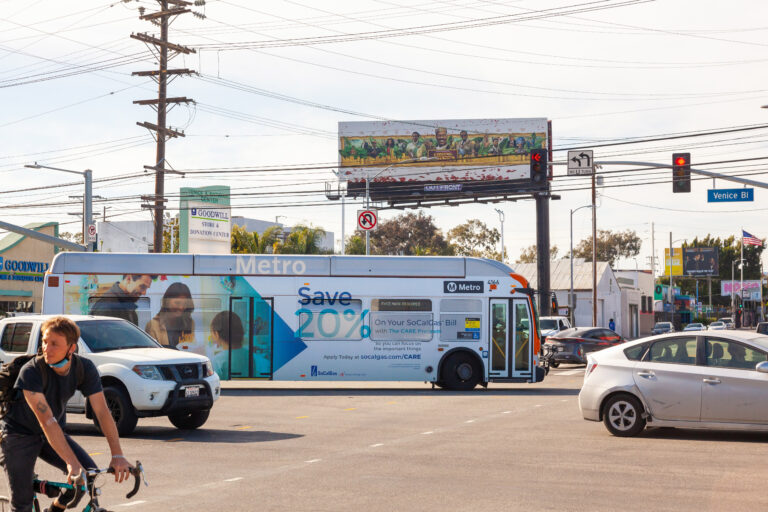 Metro Articulated Bus with white full advertising wrap passing through intersection on Venice Blvd.
