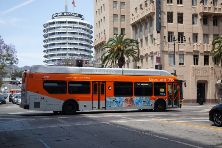 Metro Local Bus passing through intersection in Hollywood with Capitol Records building in the background.