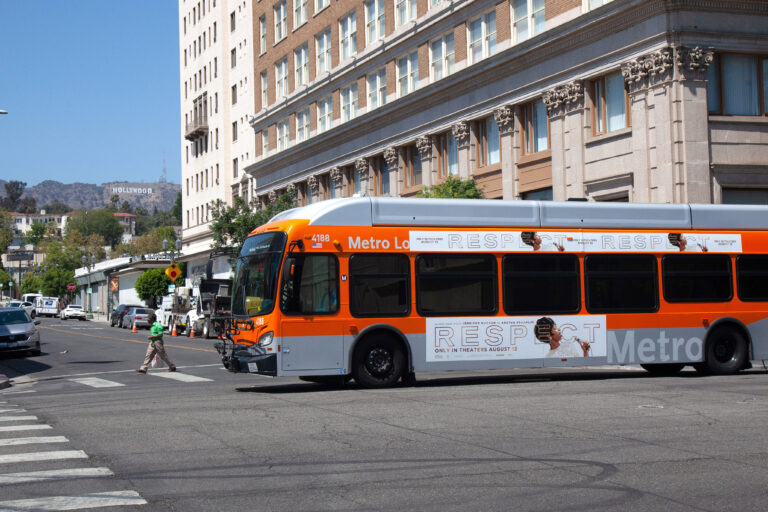 Metro Local Bus passing through intersection with Hollywood Sign in the background.