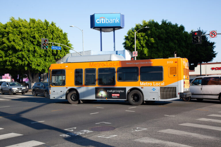Metro Local Bus with Bus Queen 2 ad on driver's side.