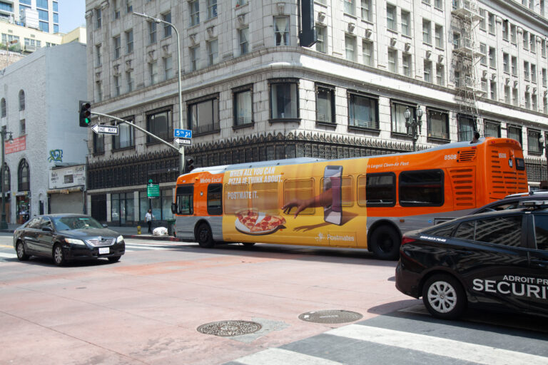 Metro Local Bus passing through 5th Street intersection with Ultra Super King Ad on driver's side.