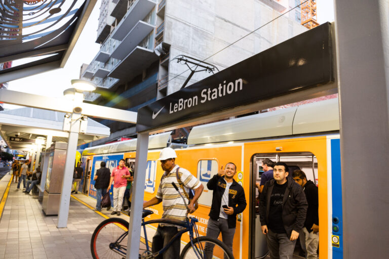 Metro Rail vehicle at Nike Lebron Station with de-boarding passengers and one pointing at the signage.