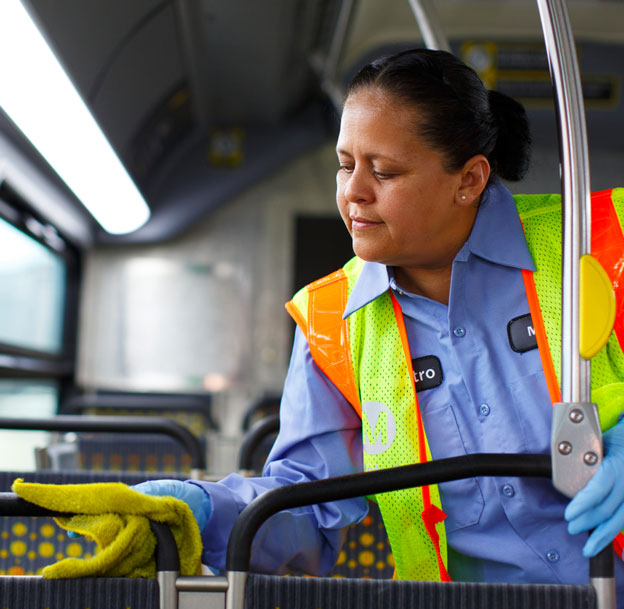 Metro staff wearing safety vest cleaning a Metro Bus.