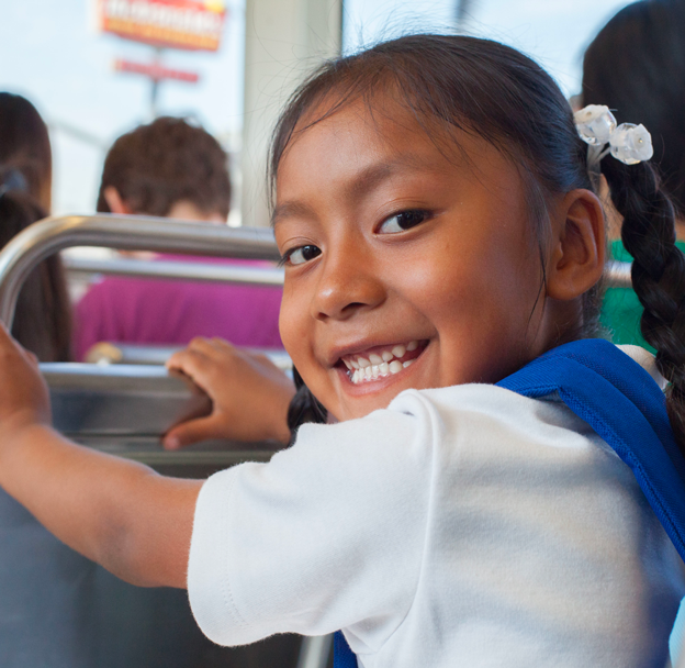 A litte girl in her school uniform looking over her shoulder behind her.